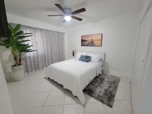 Un dormitorio blanco con una cama y un ventilador de techo. en My Tropical Paradise with pool in Miami, en Tamiami