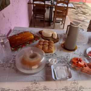 a table topped with plates of donuts and pastries at Pousada aconchego da Serra Serra do cipó in Santana do Riacho