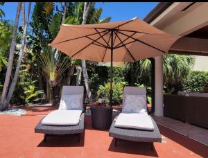 2 sillas y una sombrilla en el patio en My Tropical Paradise with pool in Miami, en Tamiami