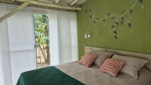 a bedroom with a bed with two pillows and a window at suíte Saíra in Ubatuba