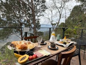 un tavolo con una colazione a base di pane e frutta su un balcone di Village dos Alpes - Chalés na Montanha Teresópolis a Teresópolis
