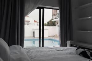 a bedroom with a view of a swimming pool through a window at Chamis Suites in Bijilo