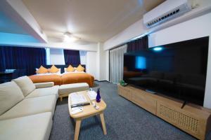 a hotel room with a couch and a tv and a bed at Miyazaki Mango Hotel - Vacation STAY 58318v in Miyazaki +21 photos