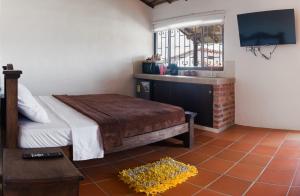 a bedroom with a bed and a sink and a television at Finca Mr Bueno Barichara in Barichara
