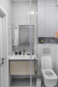 a white bathroom with a toilet and a sink at Urban Luxe U-Tower Tashkent City View Apartment in Tashkent