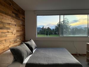 a bedroom with a bed and a large window at Countryside apartment in Rionegro