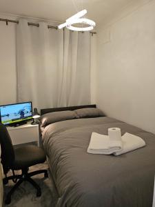 a bedroom with a bed and a desk with a computer at Eusty Guest House in Sittingbourne