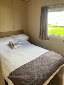 una cama con una almohada junto a una ventana en Caravan at the seaside, en Great Yarmouth