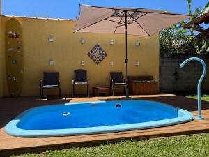 a large blue swimming pool with an umbrella at Suítes Vila Jjae in Praia do Rosa