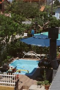 a pool with an umbrella and a table and chairs at Pousada Mar Aberto Pinheira in Pinheira