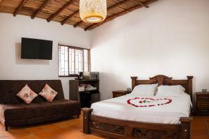 a bedroom with a bed and a couch and a television at Finca Mr Bueno in Barichara