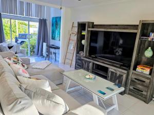 a living room with a couch and a large tv at Island House #16 at Rum Point in Driftwood Village