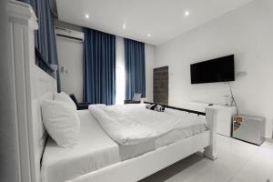 a bedroom with a white bed and a flat screen tv at Chamis Suites in Bijilo +1 photo