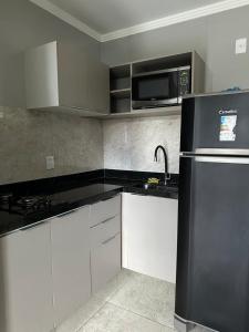 a kitchen with a black refrigerator and a microwave at Apartamento Alto Padrão - Com Ar in Campina Grande