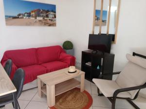 a living room with a red couch and a table at Petite maison cœur de ville de La Teste de Buch in La Teste-de-Buch
