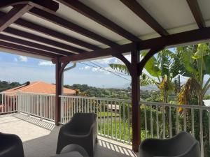 a deck with a pergola and chairs on a balcony at Maison Panorama 2 chambres in Sainte-Luce