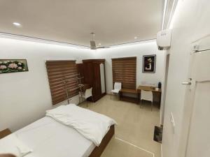 a bedroom with a bed and a desk in it at Orient Glory Holidays in Edappally