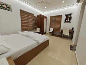 a bedroom with a bed and a desk and chairs at Orient Glory Holidays in Edappally