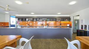 a large kitchen with orange cabinets and white chairs at The Island Accommodation in Phillip Island