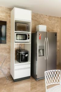 a kitchen with a microwave and a refrigerator at A Casa Paradisiaca ll Luxo Piscina Super Quente até 50 graus de Temperatura Aquecimento Elétrico com Sauna e Lavanderia com Roupa de Cama in Caldas Novas +12 photos