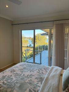 a bedroom with a bed and a view of a balcony at Killarney at Old Erowal Bay in Erowal Bay