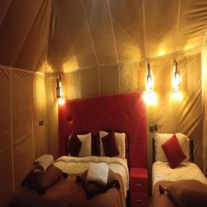 a bedroom with two beds in a tent at Starlight Erg Luxury Camp in Merzouga +15 photos