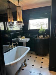 a black bathroom with a tub and a sink at La Belle Maison in Tauranga