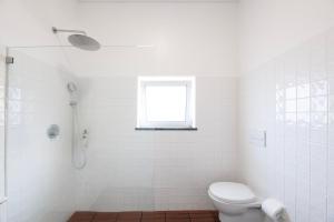 a white bathroom with a toilet and a window at Casa do Pisão - Cosy and Modern Two-Bedroom Townhouse in Angra do Heroísmo