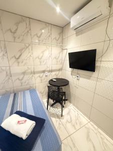 a room with a bed and a tv and a table at Cantinho aconchegante - Quarto 05 AR-condicionado in Bayeux +2 photos