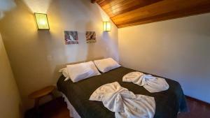 a bedroom with a bed with towels on it at Chalés Bela Vista in Monte Verde