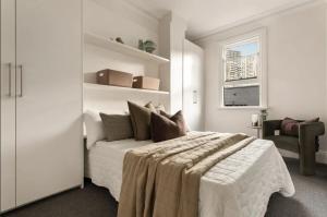 a white bedroom with a bed and a window at Stylish 4BR City Retreat Walk to CBD & Opera House in Sydney