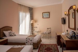 a hotel room with two beds and a desk at Dexon Roma All Inclusive Hotel in Hurghada +59 photos
