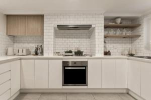 a white kitchen with white cabinets and appliances at Stylish 4BR City Retreat Walk to CBD & Opera House in Sydney