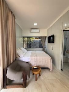 ein Schlafzimmer mit einem Bett und einem Stuhl und einem Fenster in der Unterkunft Studio Laranjeira in Palmas + 3 Fotos