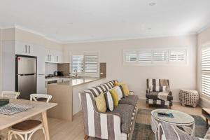 a kitchen and a living room with a couch and a table at Sunny Townhouse in Huskisson