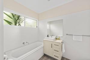 a white bathroom with a tub and a sink at Sunny Townhouse in Huskisson