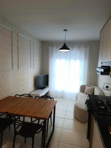 a kitchen and living room with a table and a couch at Apartamento novo, 2 quartos a 50 metros da praia in Palhoça
