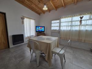 a dining room with a table and chairs and a tv at Rincón del Valle Gaiman in Gaiman