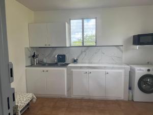 a kitchen with white cabinets and a sink and a window at Maison Panorama 2 chambres in Sainte-Luce +7 photos