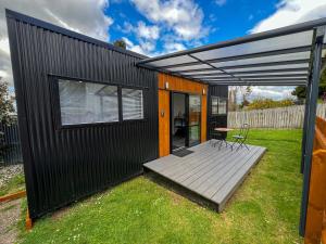 a black house with a deck and a table at Cosy Rotorua Retreat By Aotearoa Escapes in Koutu