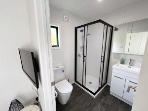 a bathroom with a toilet and a glass shower at Cosy Rotorua Retreat By Aotearoa Escapes in Koutu +7 photos