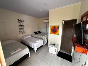 a small room with two beds and a tv at Pousada Maré do Cerrado in Mateiros