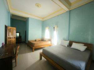 een slaapkamer met een bed en een bureau en een bed sidx sidx sidx bij Pondok Segara Guesthouse in Padangbai