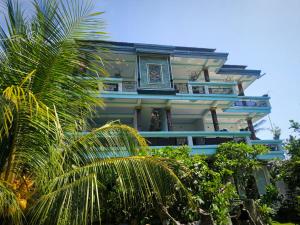 een gebouw met een palmboom ervoor bij Pondok Segara Guesthouse in Padangbai
