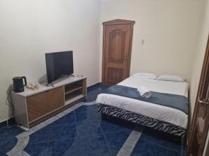 Un dormitorio pequeño con una cama y un televisor. en Casa Blanca alojamientos, en Manta