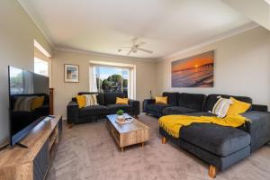 Una sala de estar con dos sofás y un televisor de pantalla plana. en Capel Grand Villa - Pet-Friendly Beach Escape, en Rosebud