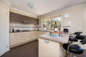 Una cocina con una botella de vino en la encimera. en Capel Grand Villa - Pet-Friendly Beach Escape, en Rosebud