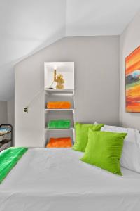 a bedroom with a white bed with green and orange pillows at Roomy Central Hub, Games, Fire Pit & Downtown Fun in Oshkosh
