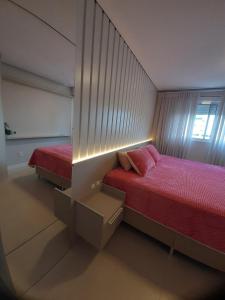 a small bedroom with two beds and a mirror at Apartamento in Imbituba