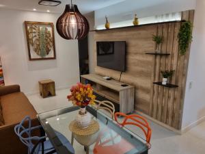 a living room with a glass table and a television at Apartamento Frente pra Praia em Resort in Arraial do Cabo